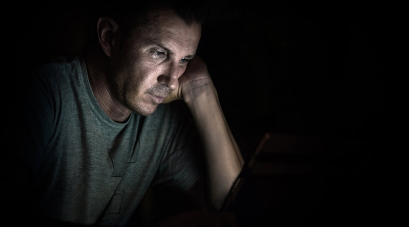 Mann kuckt op Laptop-Schierm