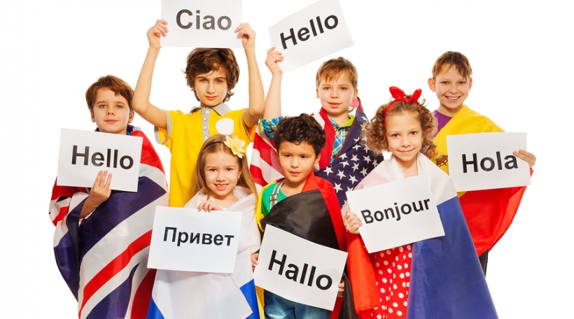 Kids wrapped in flags of USA and European nations, holding greeting signs in different languages, isolated on white