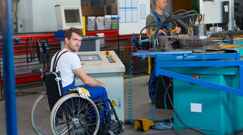 disabled worker in wheelchair in factory on the machine