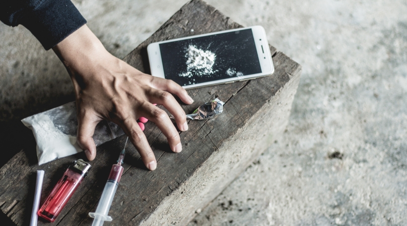 Young human hand trying to reach drugs, The concept of crime and drug addiction. 26 June, International Day Against Drug Abuse and Illicit Trafficking